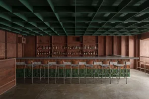 An inviting bar area with a long wooden countertop, stools, and various bottles, creating a comfortable space for socializing