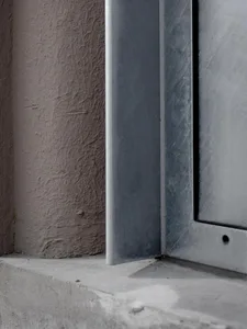 A building facade with a grey metal window frame, set against a neutral background