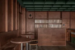 Cozy room with dark wood paneling, a bar area with wooden tables and chairs, and a bookshelf filled with books