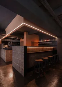 Inviting bar area with counter seating, stools, and bottles of beverages, set in a comfortable atmosphere