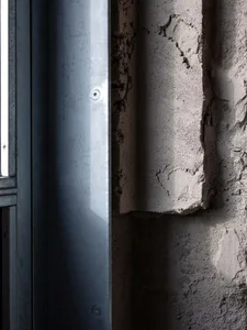 A dimly lit indoor space with a rusty metal pipe and concrete walls, featuring gray and brown colors
