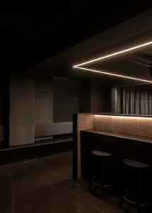 Intimate bar area with stools and a couch in a darkened environment