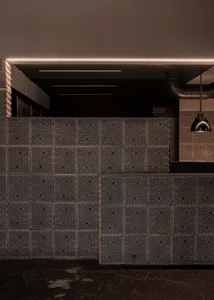 Warm and inviting room with a wooden panelled wall featuring a unique pattern, illuminated by two lights on either side