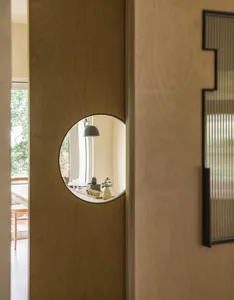 Interior design featuring a wooden wall with a large mirror and potted plants, surrounded by vases and decorative elements