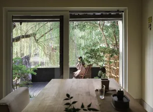 Wooden dining table with two chairs and potted plants, surrounded by a cozy atmosphere