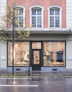 A restaurant interior with large windows, dining tables, and chairs, creating a welcoming atmosphere for customers