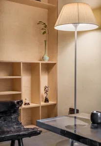 Wooden walls and floors, bookshelves, a potted plant, and a vase create a cozy atmosphere in this inviting living area