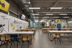 Bright and inviting cafeteria area with multiple dining tables and chairs, creating a sense of depth and ample seating options