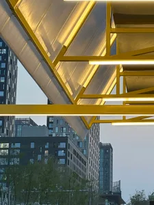 A cityscape with tall buildings, a large yellow bridge structure, and a diverse range of architectural styles