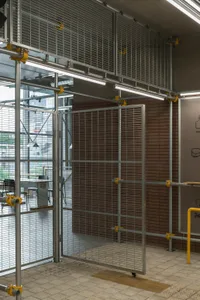 Industrial workspace with metal gate, chairs, and a dining table, giving off an impression of functionality and organization