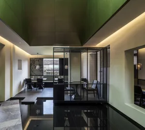 Modern dining room with a green ceiling, multiple chairs around a dining table, and several couches for additional seating