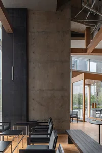 Empty modern restaurant interior with concrete walls and floors, featuring a dining table and chairs in a minimalist setting