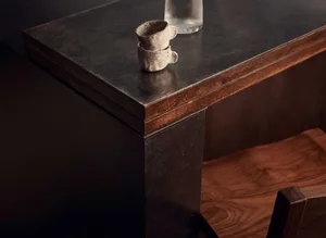 A wooden table with a black countertop features two cups and a bottle, set in a cozy and inviting space