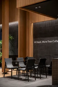 A modern cafe with black chairs and tables, black and white tile walls, and a comfortable atmosphere for patrons