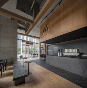 A modern restaurant interior with wooden floors and walls, featuring a bar counter and dining tables with chairs, creating an inviting atmosphere for socializing and dining