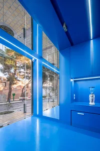 Open kitchen with bright blue walls, a large window, and a countertop with a blender and a bottle