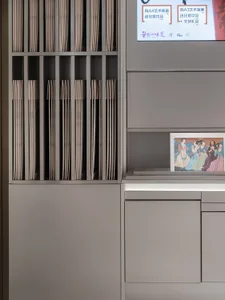 灰色櫃體搭配畫框與電視，周圍環繞書籍，提供充足收納空間