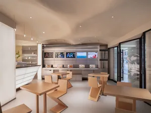 A modern art gallery with seating areas, TV screens displaying artwork, and an inviting atmosphere