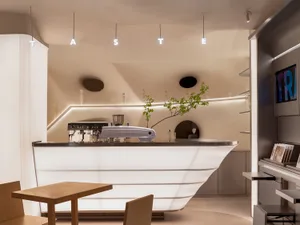 Sophisticated restaurant bar with a modern counter, two chairs, and various items on display, set in a well-lit environment