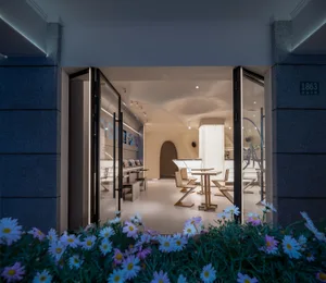 Open living area with a dining table, couches, and a TV, surrounded by modern furniture and natural light