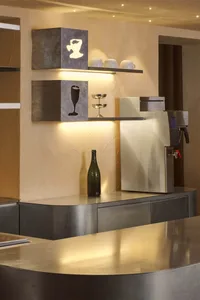 A kitchen area with a countertop featuring bottles, cups, and a vase, suggesting a cozy and functional living space