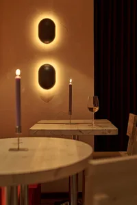 Dining area with a wooden table, two wine glasses, lit candles, and a chair, creating a warm and intimate atmosphere