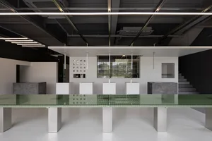 Empty minimalist room with a glass table and chairs, well-lit with natural or artificial light