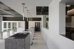 Empty modern kitchen with black countertops, multiple sinks, and a minimalist design