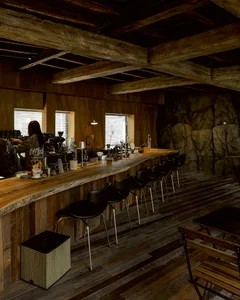 Modern bar area with a wooden countertop, stools, and chairs, creating a warm and inviting atmosphere