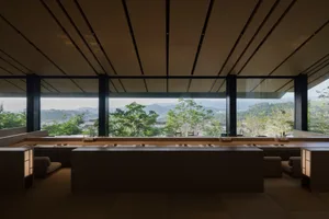 Empty industrial kitchen with wooden countertops, multiple sinks, and a large window providing an outside view