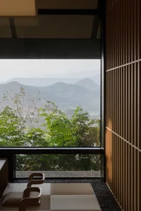 建築物寧靜外觀，擁有眺望遠方山景的大型窗戶，周圍環繞樹木