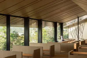 A warm and inviting restaurant interior with wooden benches and tables, natural light, and ample seating options
