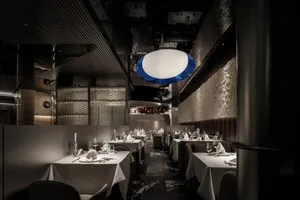 Empty restaurant with dining tables and chairs, wine glasses on some tables, inviting atmosphere