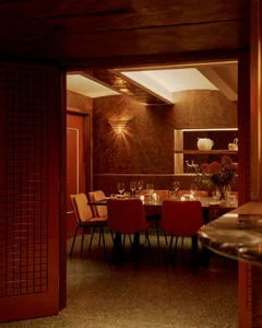 Elegant dining area with a large wooden table and chairs, wine glasses, and a sophisticated atmosphere