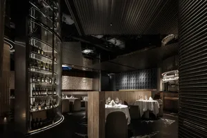 Sophisticated dining space with multiple tables, chairs, and wine glasses, set amidst tasteful decorations and well-lit spaces