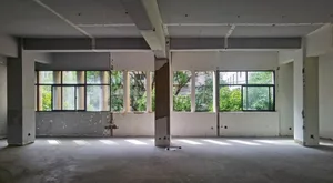 Empty white building with large windows and concrete pillars, suggesting a recently renovated or under-construction space