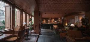 Warm and inviting restaurant interior with wooden floors, brick walls, and a tiled ceiling, featuring multiple chairs and dining tables