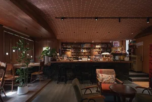 Cozy bar area with a wooden countertop, bottles, chairs, and a dining table