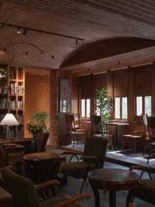 Dining area with wooden tables and chairs, potted plants, and a modern atmosphere