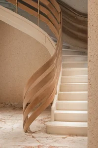 A spiral staircase with a wooden railing and marble steps in a luxurious setting with a sophisticated atmosphere