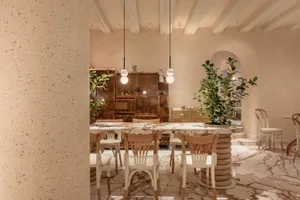 A modern kitchen with a dining table, wooden cabinets, and countertops, surrounded by potted plants and featuring ample storage and workspace
