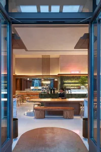 A warm and inviting restaurant interior with a large wooden dining table surrounded by chairs and cups, creating a comfortable atmosphere