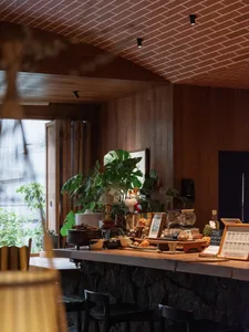 Interior design showroom with a wooden countertop, potted plants, vases, and a dining table, creating a warm and inviting atmosphere