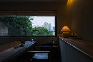 Cozy living space with a dining table near a window, allowing natural light and a view of the city outside
