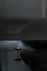 A cozy indoor space with a lit candle on a table in front of a silk curtain, creating a warm and intimate atmosphere