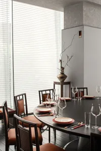 A formal dining area with a round table and chairs, wine glasses, and a sophisticated atmosphere