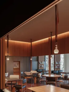 A warm and inviting hotel lobby with wooden floors, multiple chairs, and dining tables, creating a cozy atmosphere