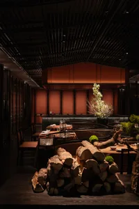 Cozy restaurant interior with wooden walls, tables, and chairs, surrounded by potted plants and natural elements