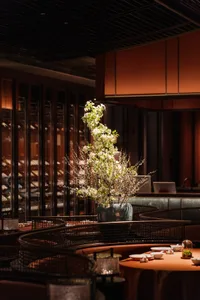 A dining area with a wooden theme, a large vase, and wine glasses, creating a sophisticated and welcoming atmosphere
