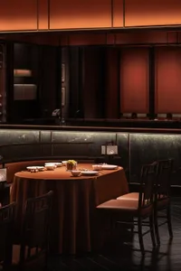 A cozy dining area with a round table surrounded by chairs, featuring various tableware and wine glasses, set in a warm and inviting atmosphere